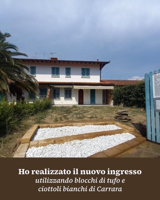 Italian villa with newly constructed entrance using white tufa blocks and pebbles, featuring palm trees and green shutters