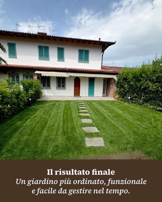 Two-story Italian villa with white walls, terracotta roof, and green shutters, featuring a manicured lawn with stepping stones leading to the entrance